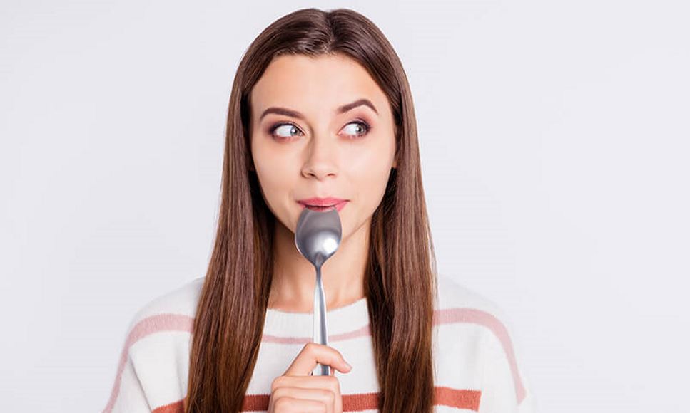 woman holding spoon in her mouth
