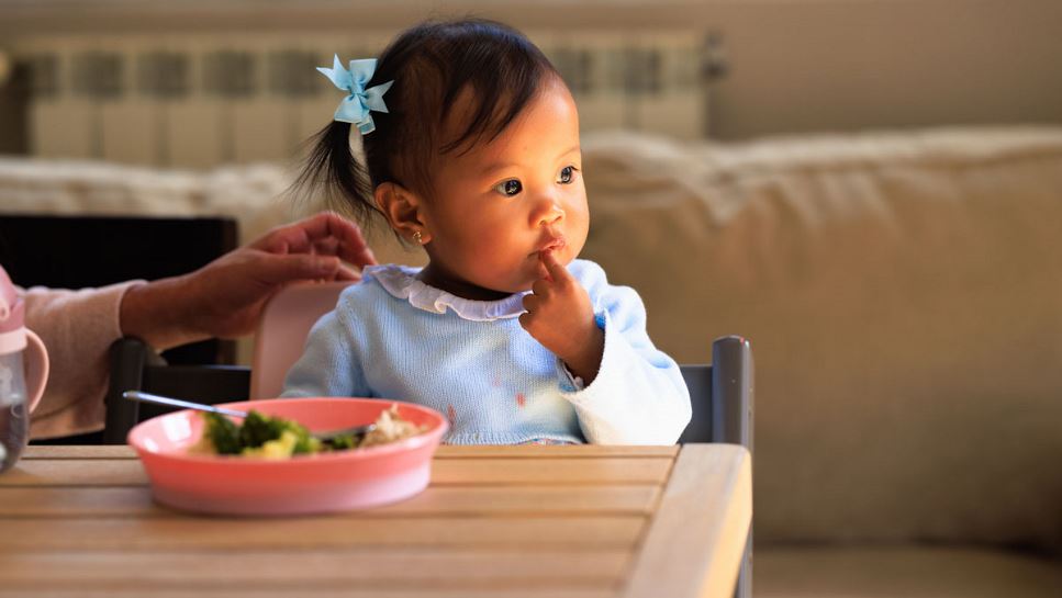 Toddler girl eating foods with vitamin C.