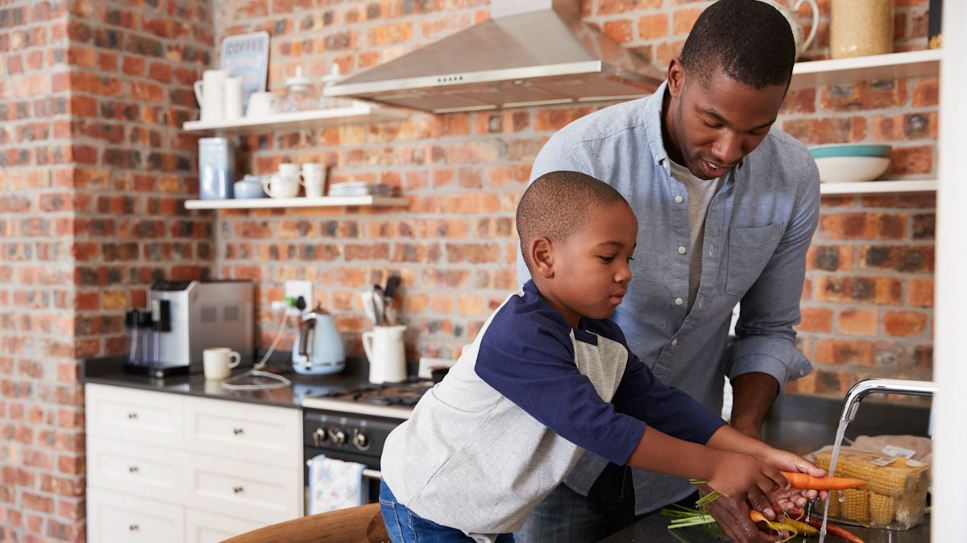 Son helping father wash vegetables for dinner